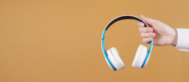 黄色背景下，男性手持白色耳机。图片下载