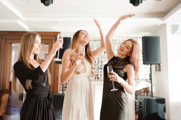 微笑的朋友拿着香槟在酒吧跳舞的肖像。图片下载