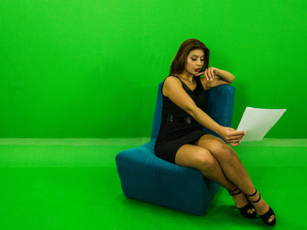 优雅美丽的女人坐在优雅的服装与绿色的背景图片下载