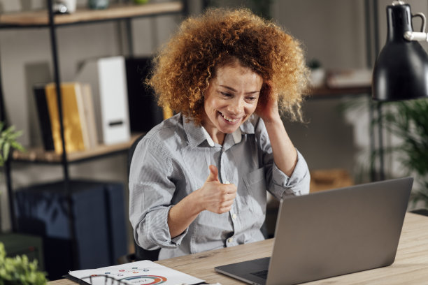 视频通话中微笑的卷发女商人。库存图片图片下载