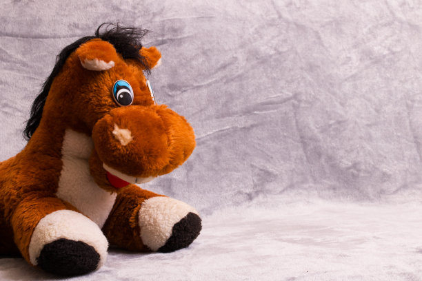 灰色背景上柔软的毛绒玩具马图片下载