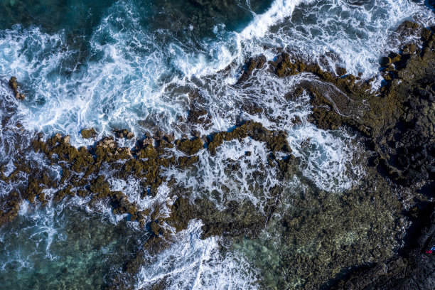 无人机拍摄的强大海浪包围着夏威夷岩石表面的照片图片下载