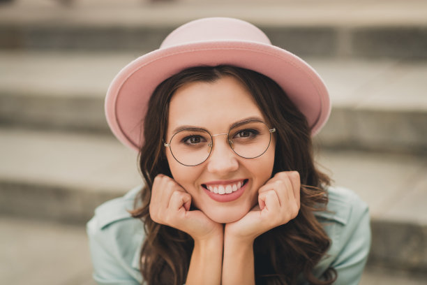 照片的梦幻，体贴的年轻女子穿着蓝绿色夹克眼镜，坐在楼梯，手臂下巴户外城市城市图片下载