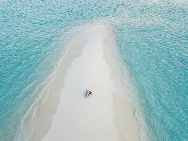 一对年轻的成年夫妇一起躺在马尔代夫碧绿的沙滩上图片下载