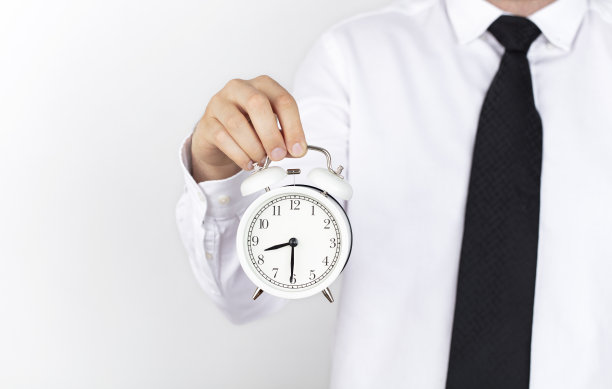 孤立的商人手上拿着一个白色背景的闹钟。图片下载