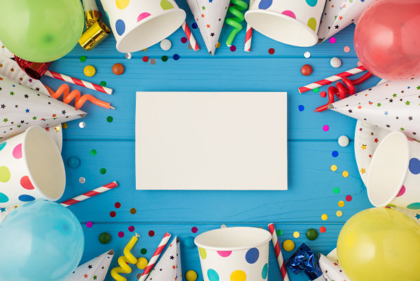 顶视图照片生日聚会组成白色卡片与copyspace在中间螺旋蜡烛管道条纹草帽气球纸杯盘子在孤立的蓝色木制桌子背景图片下载