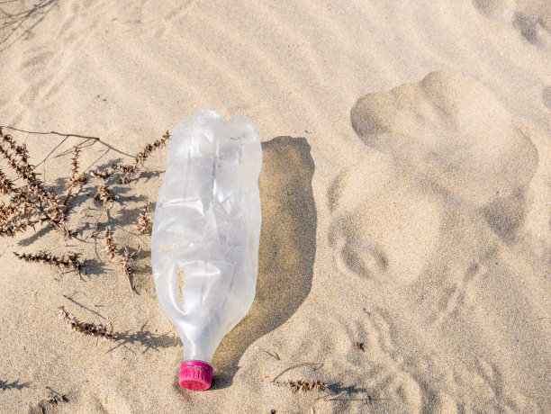 一个被留在沙滩上的PET塑料瓶。塑料污染环境理念。图片下载