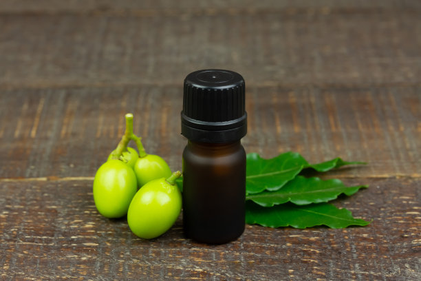 印楝油瓶和印楝叶与水果在木制背景。图片下载