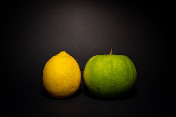 黄色的柠檬和绿色的苹果在黑暗的背景图片下载