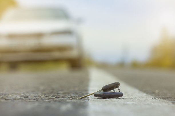 车钥匙掉在柏油路上。司机丢了车钥匙就走了。不幸的概念。用散景效果模糊前景和背景图片下载