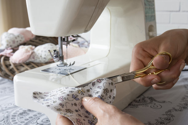 双手在缝纫机上工作。她正在用剪刀剪布图片下载
