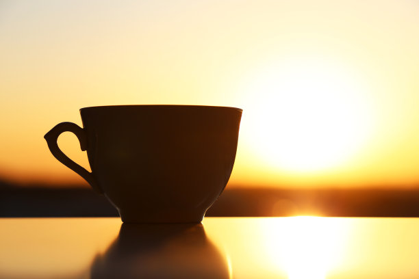咖啡杯的剪影在日出的背景下，清晨的新鲜开始图片下载