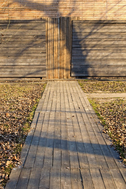 抽象的背景。穿过地面到公园的木墙的木制小路。木制的乡村木板纹理。破旧的棕色木板图片下载