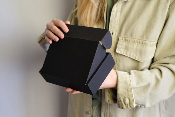 女人手里拿着一个黑色的小盒子。带着新包裹的年轻女孩。特写镜头。是时候打开节日礼物了。邮政服务,交货。牛皮纸。礼物盒,礼物。纸箱情况图片下载