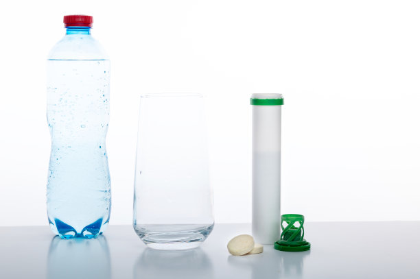 喝水瓶、玻璃杯和维生素。装有水和药丸的玻璃杯。白色背景。图片下载