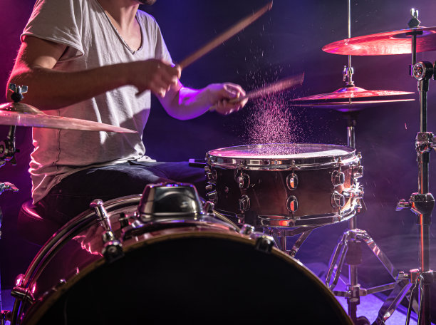 鼓手打鼓。美丽的蓝色和红色背景，与光线。美丽的特效烟雾和灯光。演奏乐器的过程特写照片。图片下载