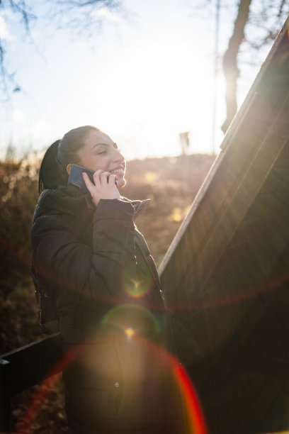 一个侧面有手机的年轻女子。库存图片图片下载