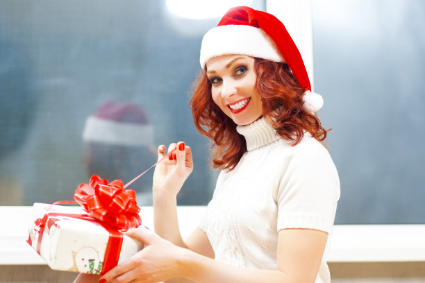 季节性节日的想法。快乐微笑的白人圣诞老人助手女孩拆开圣诞礼物盒的肖像。水平的形象图片下载