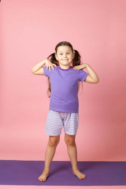 全身像的微笑女孩做晨练和热身运动的肩膀和背部的肌肉，孤立在一个粉红色的背景图片下载