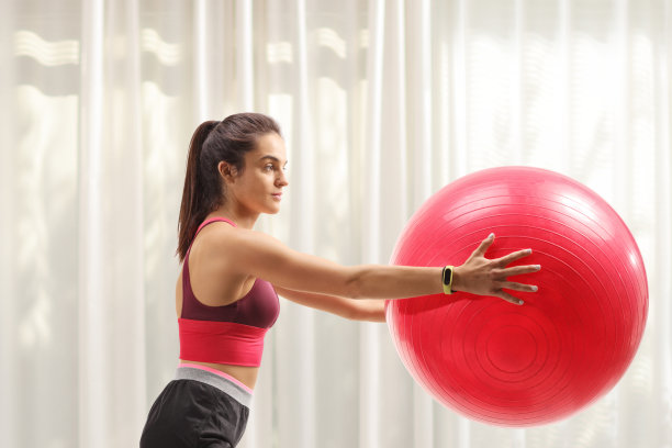 年轻女子在家用健身球运动图片下载