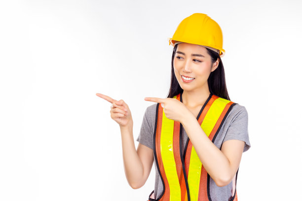 幸福美丽的年轻工人女人与孤立的白色背景指向手指和看复制空间插入广告幸福和笑脸美丽的工程师女性肖像图片下载