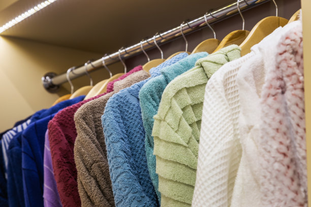 不同颜色的浴袍挂在浴室的衣架上，在商店图片下载