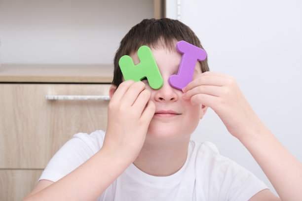 一个友好的男孩展示了一个由彩色字母组成的单词Hi，介绍和友谊概念图片下载