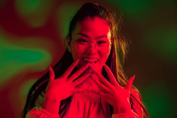 年轻美丽的亚洲女孩孤立在红绿色霓虹灯的背景。图片下载