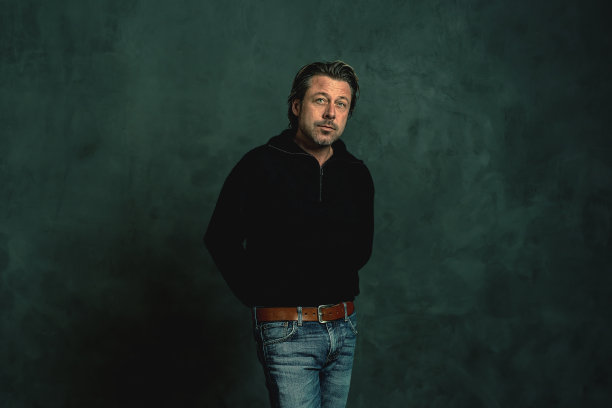 穿着黑色羊毛衫的胡子拉碴的男人靠在灰色的墙上图片下载