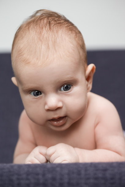 微笑的新生儿男孩平静地躺在针织毯子上的特写。垂直的图像图片下载