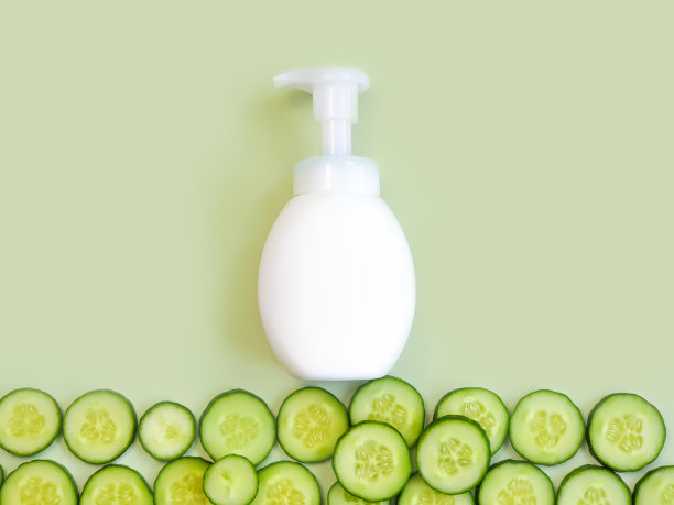 白色无商标泵瓶和黄瓜片在浅绿色的背景。装乳液、乳霜、防晒霜、洗发水或护发素的空白容器。样板造型，化妆品广告图片下载