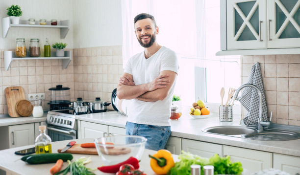 胡子微笑的英俊男子在厨房里摆姿势，看着镜头图片下载