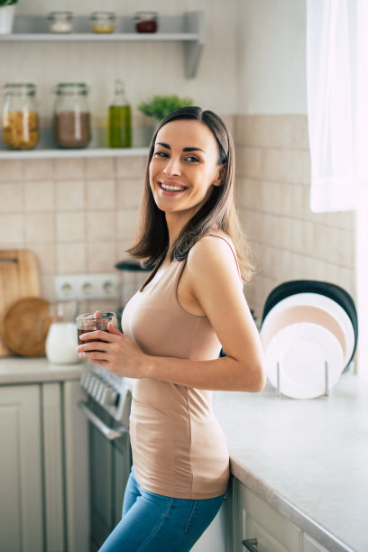 美丽的微笑年轻的黑发女人喝美妙的咖啡和放松在家庭厨房在周末图片下载