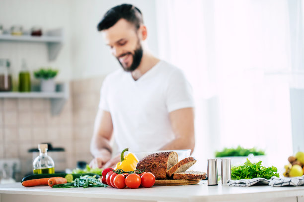 英俊的微笑年轻的胡子男子厨师新鲜健康的素食沙拉为他的家人和有乐趣在大灯光厨房图片下载