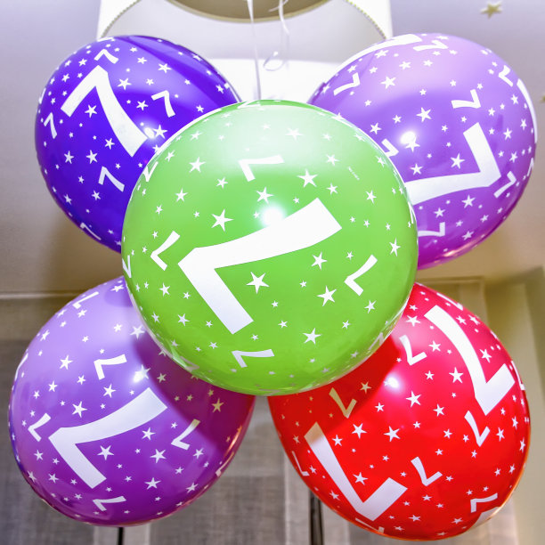 气球悬挂在一个房间的灯与数字7，生日气球不同的颜色和星星图片下载