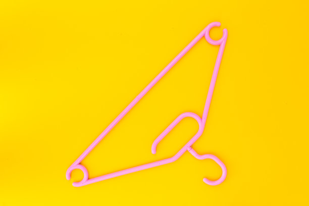 黄色背景上的粉色塑料衣架。图片下载