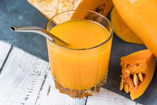 木桌上放着金属管的果汁。南瓜饮料作为健康食品图片下载