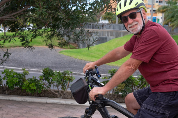 年轻的老年人在城市公园里骑着自行车活动。迷人的白发退休老人享受积极和健康的生活方式图片下载