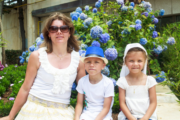 家庭时间。快乐的妈妈带着孩子坐在盛开的绣球花旁边，拍了一张彩色的照片图片下载