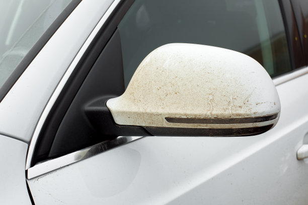 后视镜覆盖一层粘连污垢白色汽车与转向灯外镜车身特写。图片下载