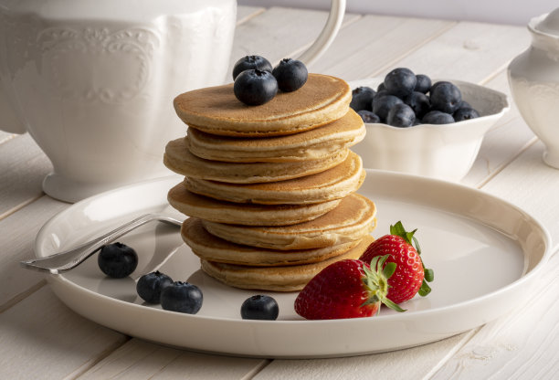 特写美味的煎饼，与新鲜的蓝莓，草莓在一个白色的木头背景，煎饼库存照片图片下载