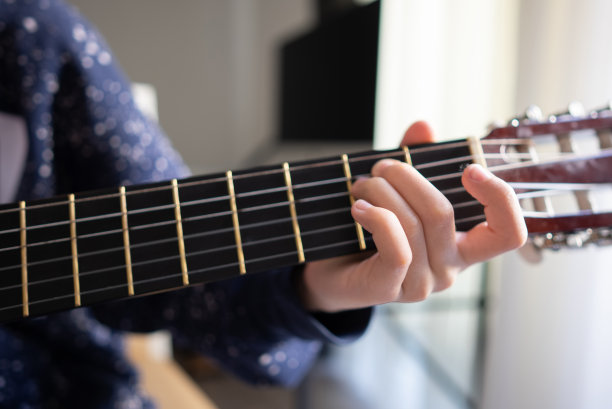 一个小男孩的手指在指板上弹奏和弦的特写图片下载