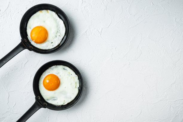 煎蛋配樱桃番茄和早餐面包在铸铁煎锅里，白色背景，俯视图平铺，有文字空间图片下载