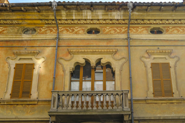 巴洛克式的黄色建筑立面，有窗户和百叶窗，阳台在中心有植物图片下载
