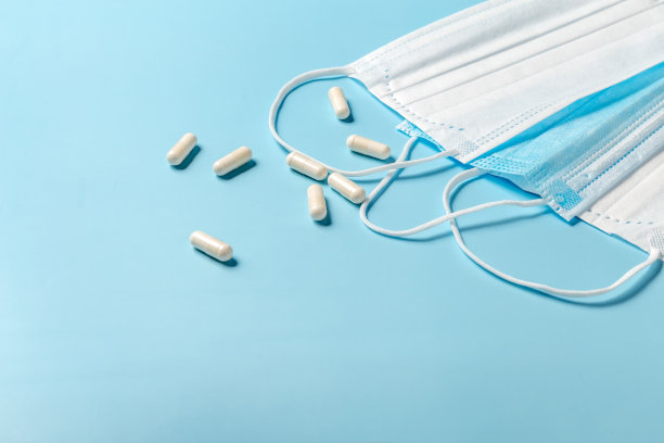 蓝色桌子上的一次性医用口罩和药片。图片下载