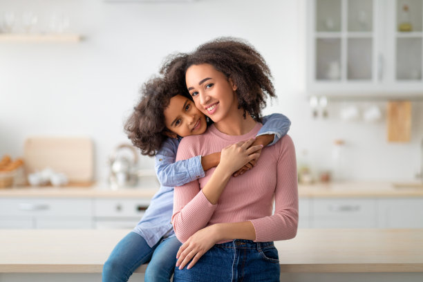 非裔美国人女儿从后面拥抱她微笑的妈妈素材图片