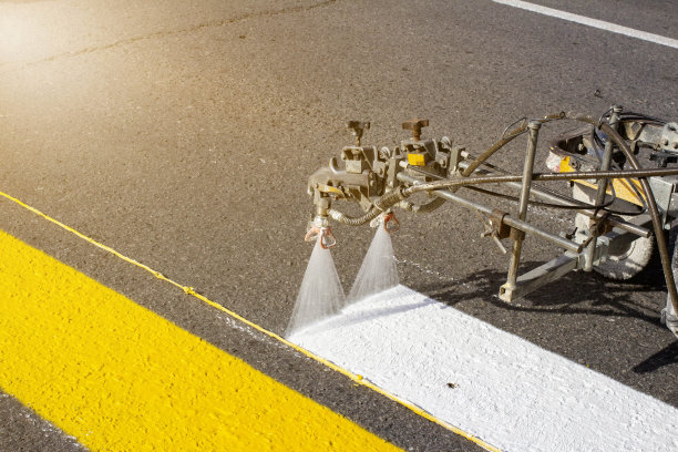 早春，一组工人在新铺的柏油路上使用自动化设备绘制人行横道图片下载