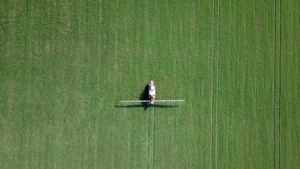 农业喷洒：农用机械向绿色田野喷洒农药图片下载
