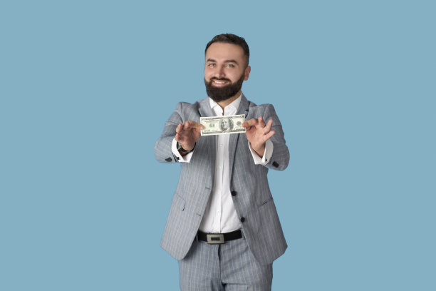 积极的年轻的公司员工持有100美元钞票在蓝色的工作室背景图片下载