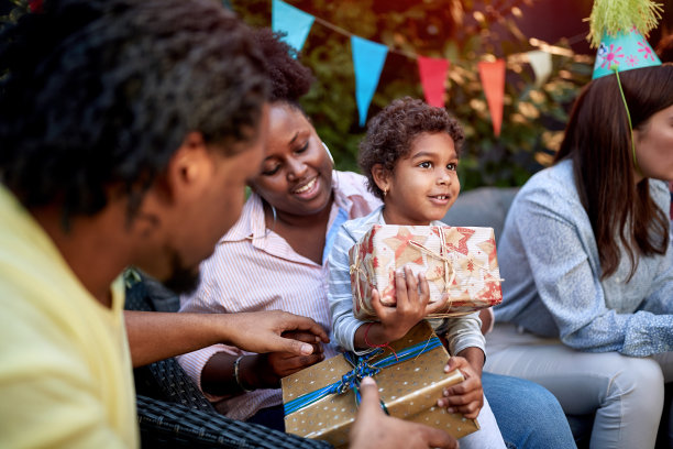 年轻的美国黑人父母抱着女儿，手里拿着生日礼物图片下载